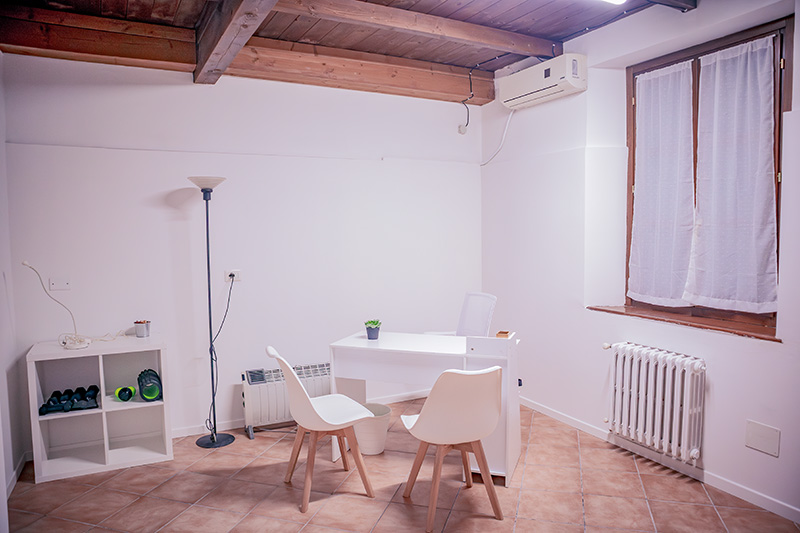 Spazio professionale con scrivania e due sedie, ideale per colloqui privati o fisioterapisti, disponibile per l'affitto.