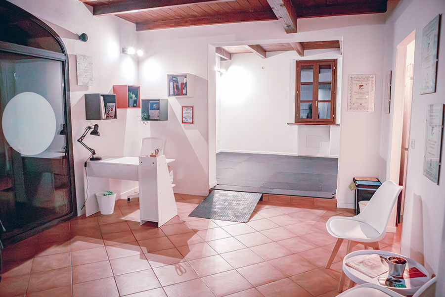 Reception del centro di fitness adattato Adapt, una stanza con i muri bianchi e i pavimenti in cotto che accoglie la scrivania della segreteria e delle sedie da sala d'attesa.