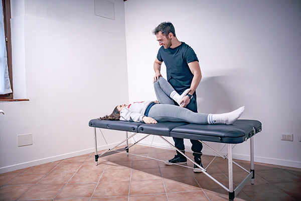 Un fisioterapista intento a svolgere un trattamento a una paziente sul lettino.